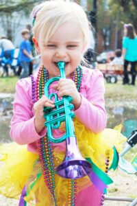 Cruising out of New Orleans | Child play's horn during Mardi Gras while covered in beads